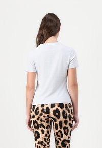 Απαλό μπλε κοντομάνικο μπλουζάκι με στρογγυλή λαιμόκοψη, συνδυασμένο με κολάν σε μαύρη και καφέ λεοπάρ εκτύπωση με λεία υφή.