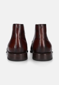 Bruine leren enkelboots met een gladde textuur, ronde neus en subtiele stiksels; gestapeld hakje en een trekhaak voor gemakkelijk aan- en uittrekken.