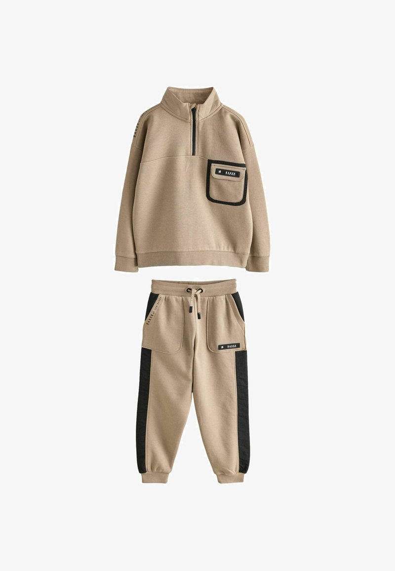 Beżowy zestaw dresowy z czarnymi panelami bocznymi, zawierający pół-zamek z kieszenią z przodu oraz spodnie dresowe z troczkiem i dużymi kieszeniami.