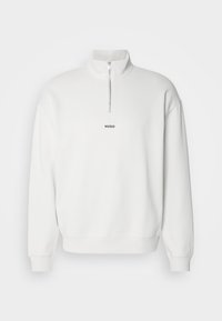 Sweat-shirt blanc à manches longues avec une courte fermeture éclair à l'avant et le logo "HUGO" centré sous la fermeture éclair sur la poitrine.