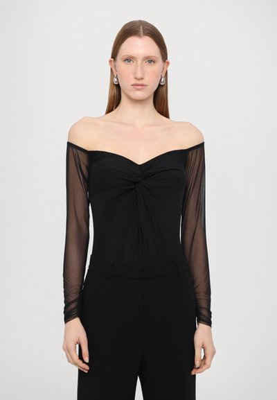 Haut noir à épaules dénudées avec des manches longues transparentes, présentant un détail de devant torsadé. Tissu lisse avec une coupe ajustée et des lignes épurées.