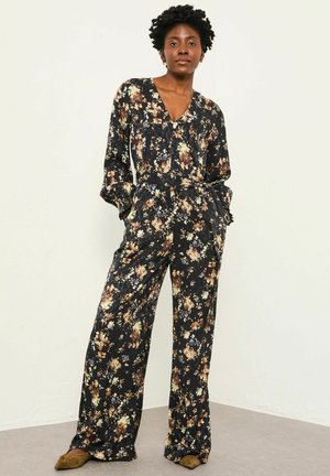 Floraler Jumpsuit aus dunklem Stoff mit V-Ausschnitt, langen Ärmeln und weitem Bein, durchgehend mit mehrfarbigen Blumenmustern versehen.