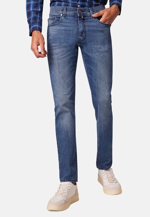 Blaue Jeans im Slim-Fit mit vorderen Taschen, leicht verkannter Textur und Druckknopfverschluss. Kombiniert mit hellen Sneakern.