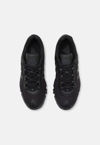 Pantofi sport negri cu o parte superioară din plasă texturată, vârf rotund și design cu șireturi. Brandul și accentele negre pe limbă și părțile laterale.