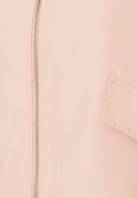 Jasnoróżowa kurtka z metalowym zamkiem w kolorze srebrnym, teksturowanym materiałem oraz małą kieszonką na górnej części rękawa.