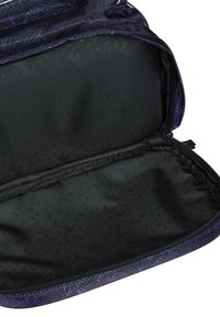 Interno di uno zaino in stoffa nera con una texture liscia, caratterizzato da una chiusura a zip con motivo viola e un design marchiato sottile all'interno.