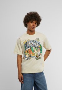 Lysbeige bomull t-skjorte med en fargerik illustrasjon med campingtema som viser trær, dyr og et telt, korte ermer og en avslappet passform.
