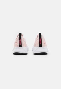 Scarpe da ginnastica rosa chiaro con una tomaia testurizzata, caratterizzate da un tallone nero e una suola bianca. Il logo del marchio è ben visibile in rosa.
