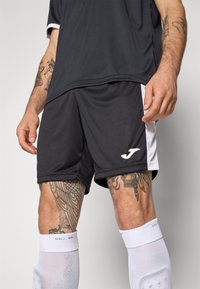 Zwarte sportshorts met witte zijaccenten, gemaakt van lichtgewicht, ademend materiaal, voorzien van een geborduurd logo en premium stiksels.