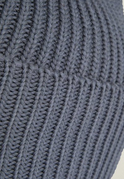 Gros plan d’un tissu tricoté gris doux montrant un motif côtelé vertical et une texture détaillée du fil.