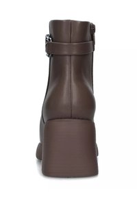 Stivaletto in finta pelle marrone con tacco spesso, chiusura con zip sul retro e cinturino laterale regolabile. Texture liscia, design minimalista.