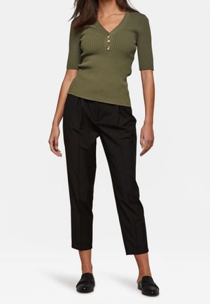 Haut à manches courtes côtelé vert olive avec trois boutons au niveau du col, associé à un pantalon noir tapered taille haute et des mocassins noirs.
