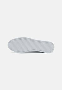 Suela de zapatilla de goma blanca con patrones de tracción horizontales y verticales, que presenta una textura suave y un tacón redondeado para una mejor adherencia.