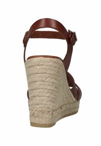 Bruine leren wedge sandaal met een geweven jute platform. Voorzien van een verstelbare enkelband en een gestructureerd oppervlak.