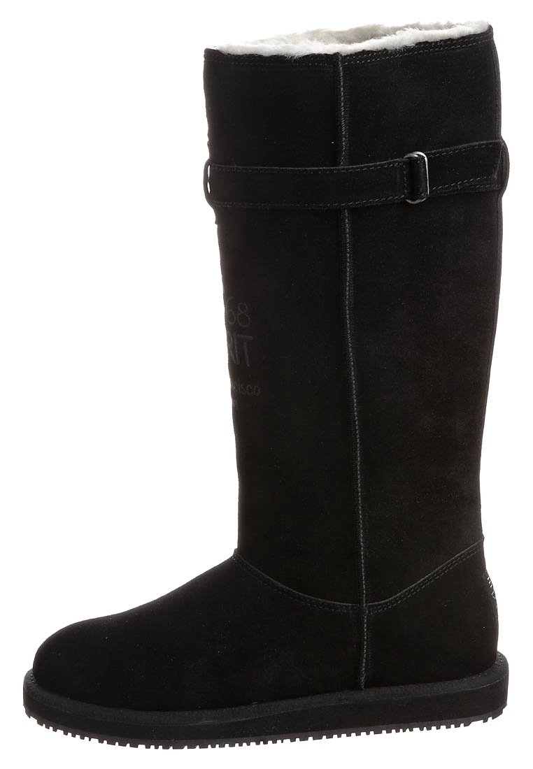 Svart mocka knähöga stövlar med mjukt vitt foder, en sidrem med spänne och en platt gummisula. Har präglad logotyp.