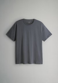 Prosta ciemnoszara koszulka na krótki rękaw z okrągłym dekoltem, wisząca na jasnoszarym tle.