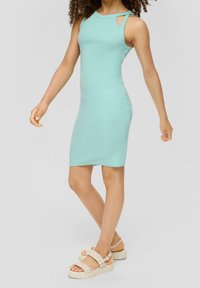 Un vestito aderente senza maniche di un verde acqua chiaro, con dettagli alle spalle tagliati; realizzato in un tessuto a coste elasticizzato che si adatta al corpo.