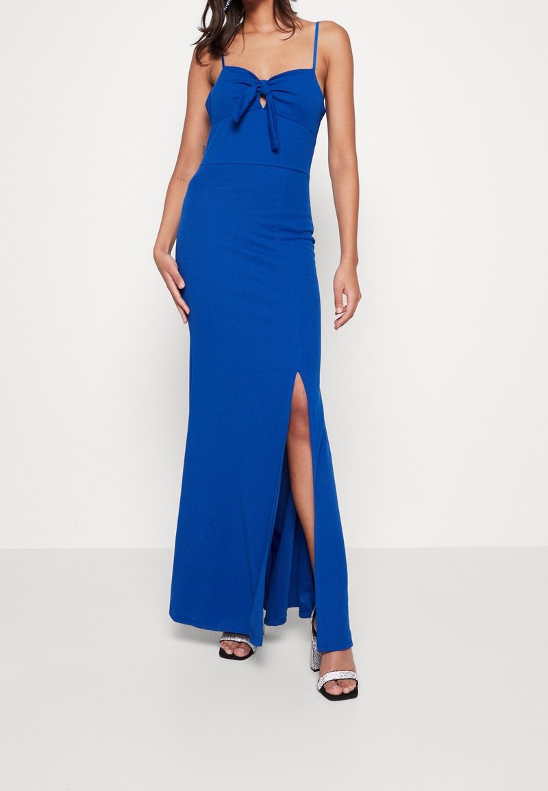 Lång, figurnära blå klänning med en knuten rosett vid halsringningen och en slits till låret. Tillverkad av ett mjukt, elastiskt tyg.