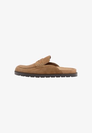 Mocassin marron en daim à enfiler avec une semelle en caoutchouc noire et des détails cousus, vu de profil sur fond blanc.
