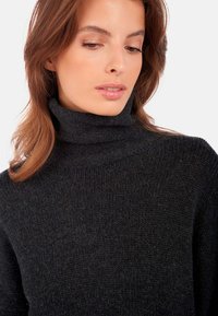 Schwarzer, gerippter Rollkragenpullover aus strukturiertem Strickmaterial. Besitzt einen hohen Kragen und eine weiche, warme Optik.