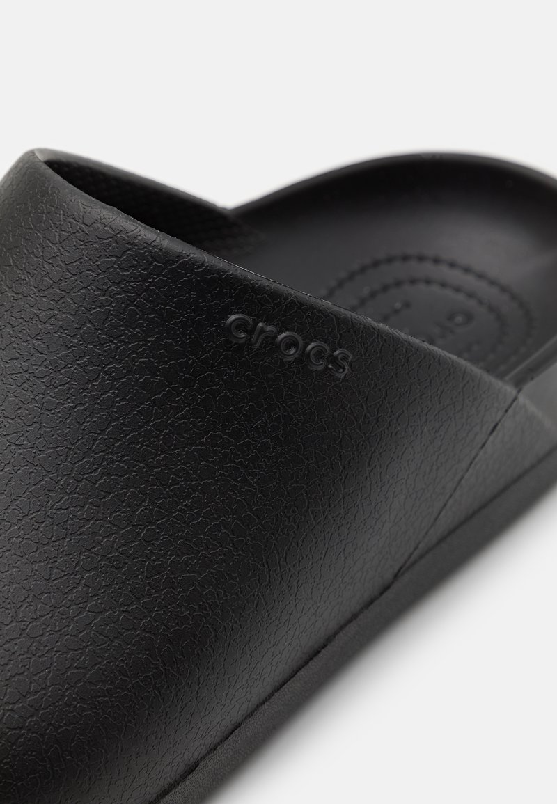 Zuecos negros de Crocs con un acabado texturizado, bordes redondeados y logo grabado. Interior suave con sutiles patrones circulares.