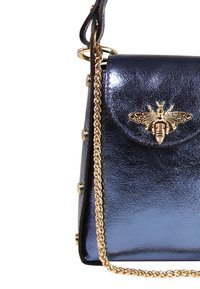 Navyblauwe patenten leren handtas met een gouden schouderriem, versierd met een bijmotief op de klep, met gouden hardwareaccenten.