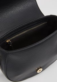Borsa a tracolla in pelle nera testurizzata con una chiusura magnetica dorata, con parte superiore aperta e tasca interna con zip.