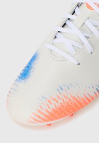 Vit fotbollssko med blå och orange gradientmönster, texturerad syntetisk ovandel och vita snören. Har en rund tå och synliga dobbar.
