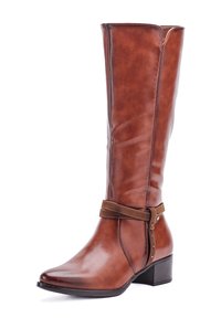 Bota alta de cuero marrón con tacón bajo de bloque y correa decorativa alrededor del tobillo sobre fondo blanco.