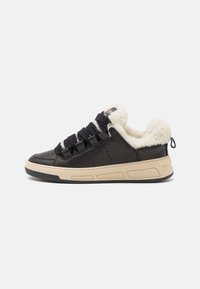 Sorte lærersneakers med en fluffy kremfarget innersåle, tykke sorte lisser, og en beige gummisåle med utskårede detaljer.