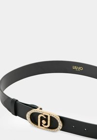Cintura in pelle nera con una fibbia ovale dorata e un accento di perla. Texture liscia e dimensione regolabile con diversi buchi per la cintura.