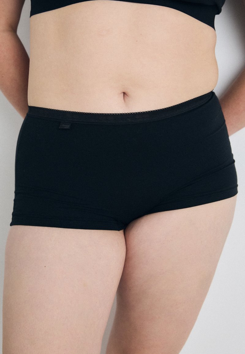 Svarta stretchiga bomullshipsterunderkläder med ett slätt midjeband och minimala sömdetaljer, med en etikett på midjebandet.