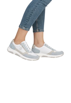 Chaussures de sport blanches et gris clair avec texture en maille et en daim, dotées d'une fermeture éclair sur le côté et d'une semelle épaisse, présentées avec un jean en denim.