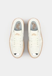 Hvide lædersneakers med perforeret design, beige gummisål og sølvdetaljer på tåboksen; med Nike Air-logo på tungen.