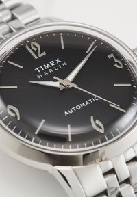 Timex Marlin wristwatch with black face, silver numerals and hands, silver stainless steel bracelet, showing 11:05:20.