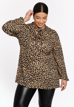 Blouse en imprimé léopard beige et noir, avec un col montant et un détail à nouer, ainsi que des manches longues ; tissu lisse, coupe ample.