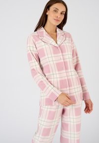 Camisa de pijama de franela a cuadros rosa con cuello con muesca y cierre de botones. Mangas largas, pantalones a juego, presenta acentos en blanco y azul en el patrón.