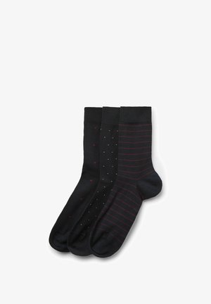 Tři páry černých ponožek s různými vzory: malé červené tečky, drobné bílé čtverečky a tenké červené horizontální pruhy.