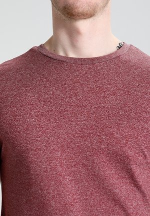 Punainen hähnämänen crew-neck T-paita, joka on valmistettu pehmeästä tekstuurista kankaasta. Paitassa on hieman muotoiltu malli ja minimaalista sauman yksityiskohtia.