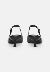 Black leather slingback heels with a pointed toe, a low stiletto heel, and an adjustable strap featuring a metallic buckle detail.