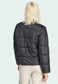 Svart puffjacka med quiltat mönster, med en kort skuren design och vida ärmar, tillverkad av glänsande, lätt material.