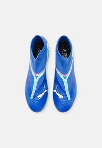 Scarpe sportive blu slip-on con una texture a maglia, caratterizzate da dettagli verde menta e branding bianco. Il design include una caviglia aderente e una forma snella.