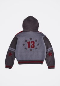 Γκρι πουλόβερ με κουκούλα σε αποχρώσεις γκρι και σκούρο γκρι, πλεκτό, με κόκκινα αστέρια στα μανίκια, κόκκινο «13» και κύκλο με σκούρα αστέρια στην πλάτη, με ριμπ τελείωμα και μανσέτες.