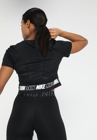 Svart kortärmad träningströja med meshdetaljer på ryggen och en kraftig märkesresår.