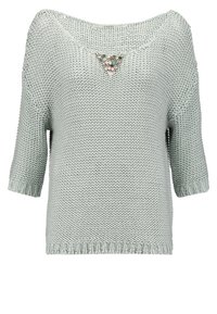 Maglione grigio chiaro a maglia con maniche a tre quarti e un dettaglio decorativo a forma di gemma triangolare sul collo.