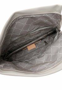 Graues Innenfutter einer Tasche mit gestepptem Muster, ausgestattet mit einer Reißverschlusstasche und einem Lederakzentanhänger. Hellbraunes Äußeres, das an den Kanten sichtbar ist.