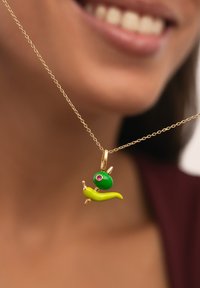 Collar de oro con un colgante de caracol caprichoso, con una concha verde y un cuerpo amarillo, acentuado por un ojo de gema rosa.