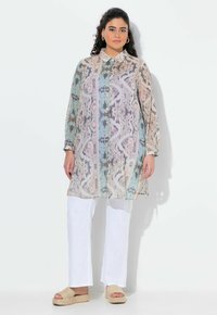 Tunika leggera con colletto in stampa astratta multicolore, maniche lunghe, chiusura con bottoni davanti, abbinata a pantaloni bianchi e sandali con zeppa.