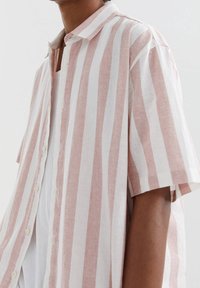 Korte mouwen, knoopsluiting shirt in lichtroze met witte verticale strepen, gemaakt van lichtgewicht stof met een relaxte pasvorm en zachte textuur.