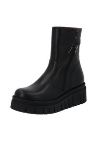 Zwarte leren enkelboot met chunky ribbelzool en zijrits op een witte achtergrond.